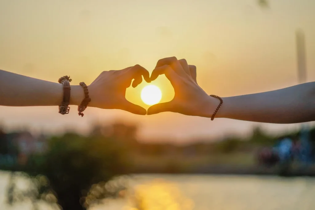 Hands forming a heart shape at sunset, symbolizing love and adventure in the best places to visit in March."