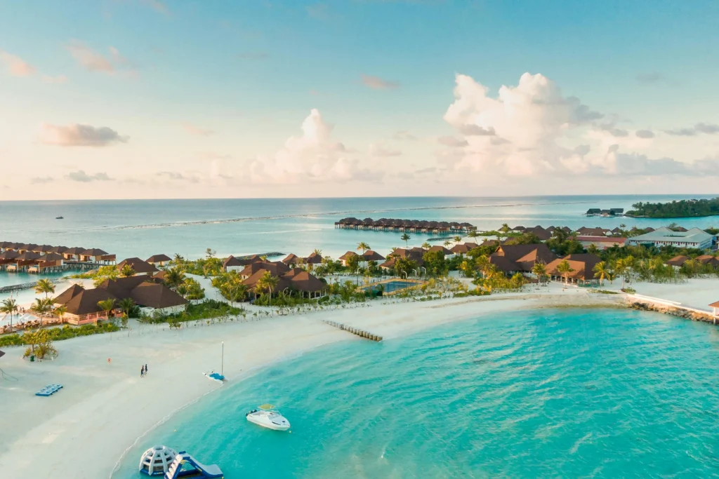 Aerial view of a luxurious island resort with overwater bungalows and clear turquoise waters, epitomizing the Maldives' tropical paradise