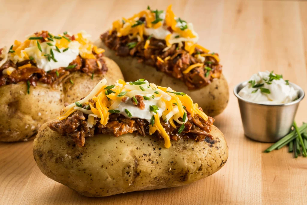 Loaded BBQ baked potato topped with melted cheese and sour cream, showcasing Southern cuisine on food tours in America.