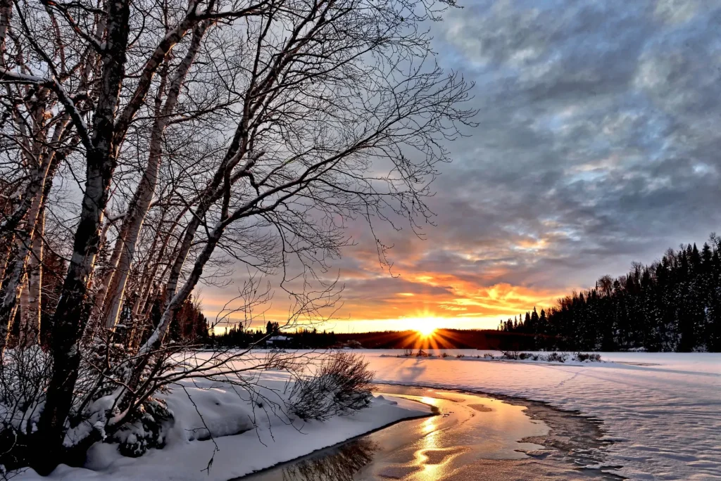  A serene winter landscape featuring snow-covered trees and a vibrant sunset sky, exemplifying the beauty of snowy destinations ideal for February travel.