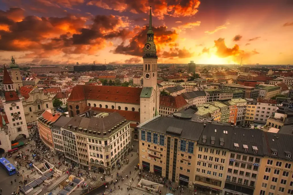 Sunset over Munich's skyline featuring high-rise buildings and a prominent tower.