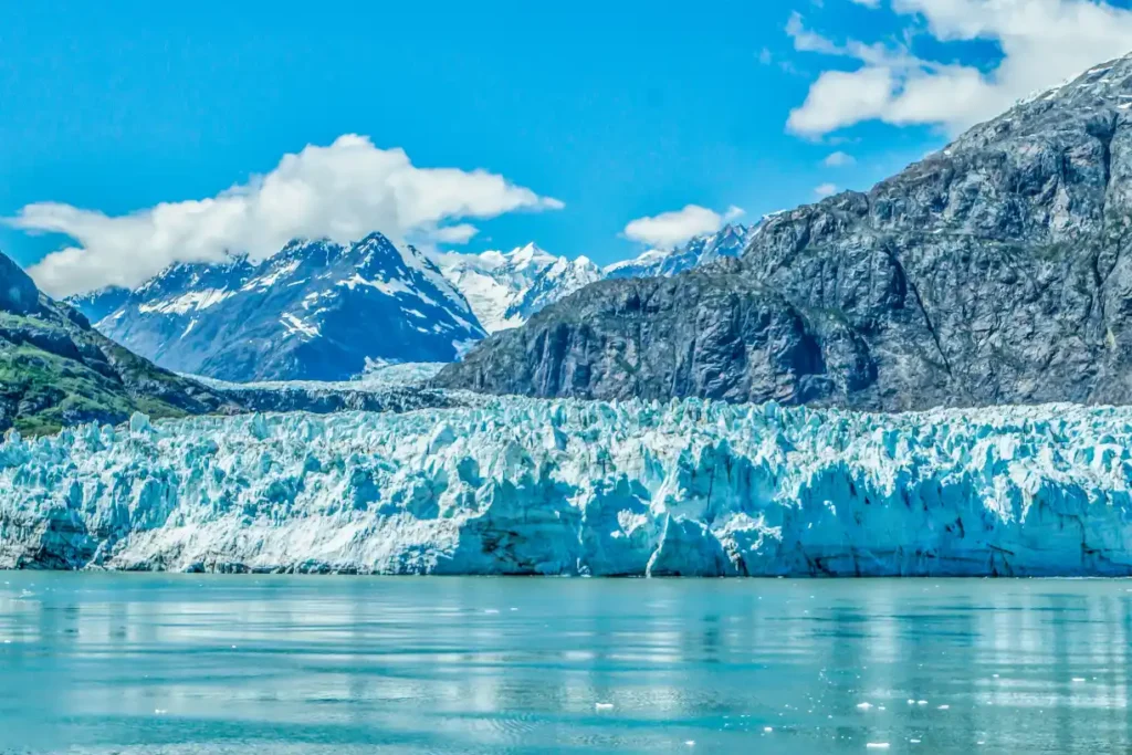 A breathtaking view of a glacier in Alaska, surrounded by towering mountains and clear blue waters, showcasing the natural beauty of one of the best places to live in Alaska.