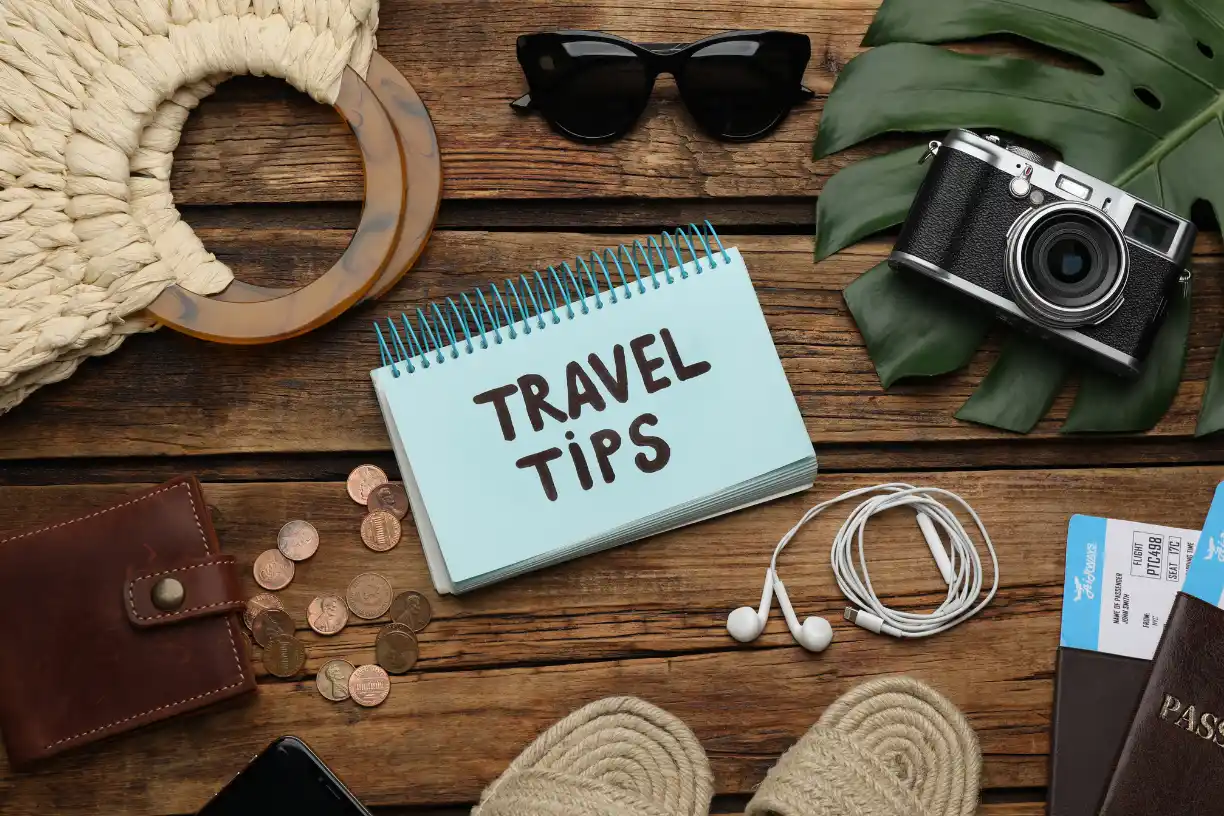 "Travel tips with essential travel items like sunglasses, passport, and camera on the ground."