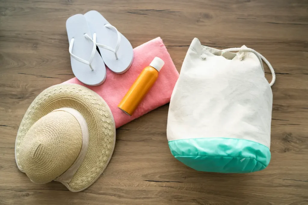  Essential Hawaii outfit accessories including a sun hat, flip-flops, beach bag, towel, and sunscreen, perfect for a tropical vacation.