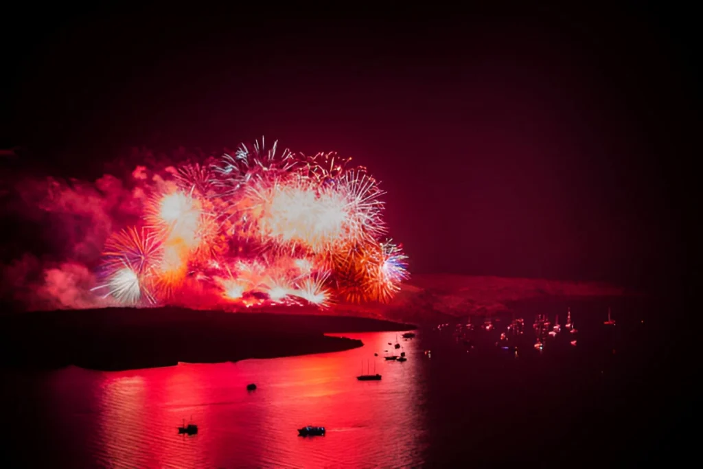 Spectacular fireworks illuminating the night sky over Santorini Greece during a vibrant festival celebration.