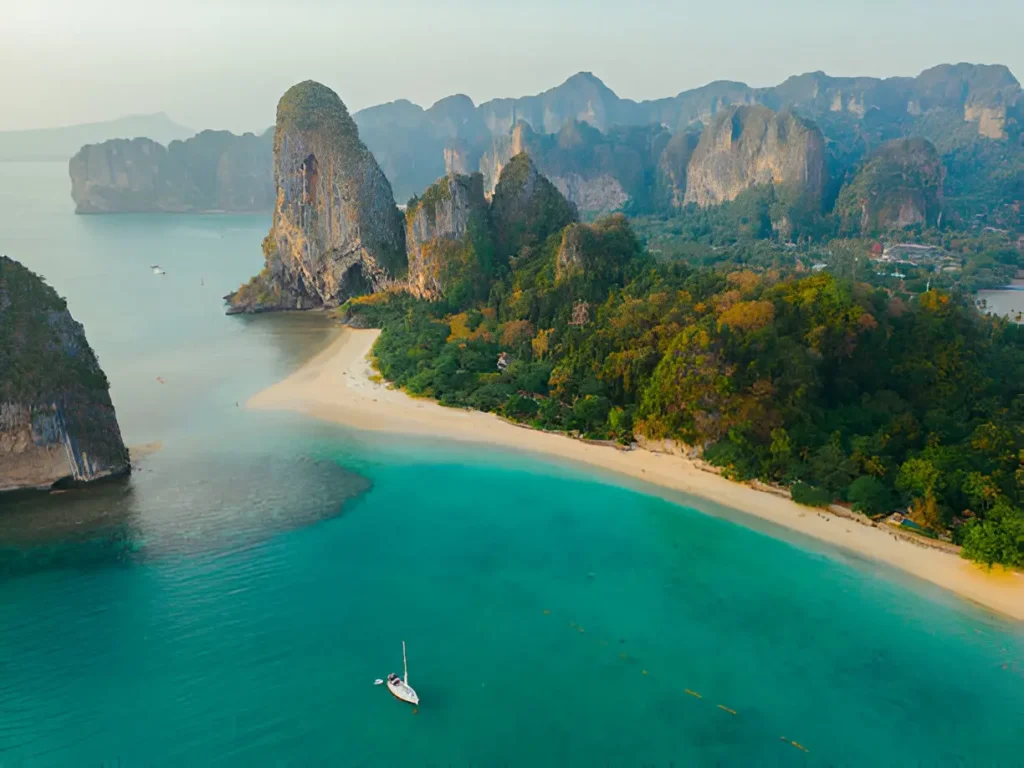 "Phuket happiness trips: Turtle Village – Aerial view of a yacht near Railey Beach in Thailand."