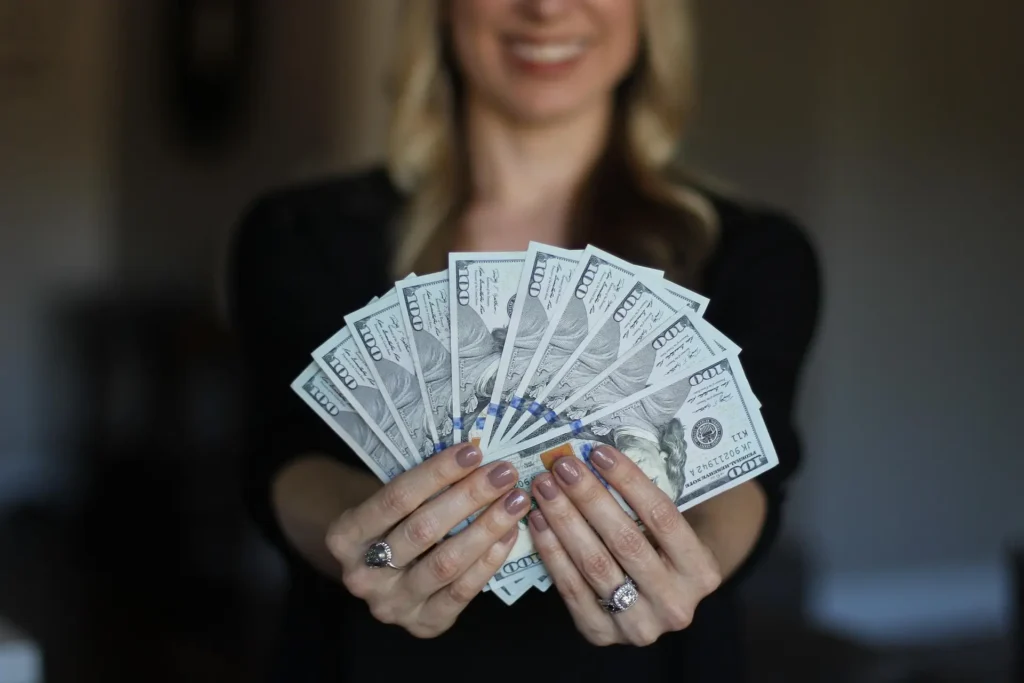 "Girl holding money with a view of the cost of living and housing market in the best cities to live in Maui."