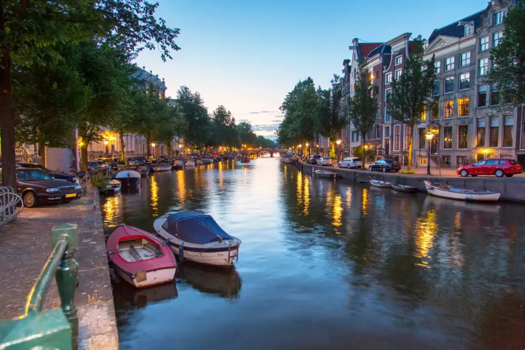 Amsterdam canal at sunset with warm lights reflecting on the water, showcasing the pleasant Amsterdam weather for May."