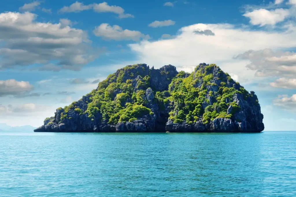 A breathtaking view of a lush green island in Ko Samui, Thailand, surrounded by crystal-clear turquoise waters under a bright blue sky.