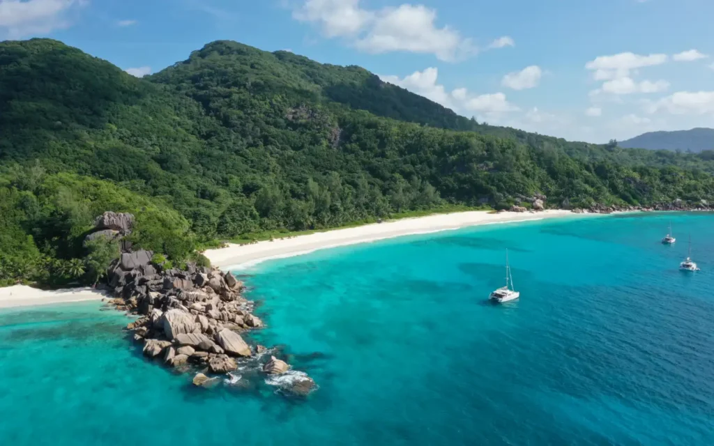 A stunning view of Seychelles with turquoise waters, white sand beach, and yachts—an ideal setting for luxury travel destinations.